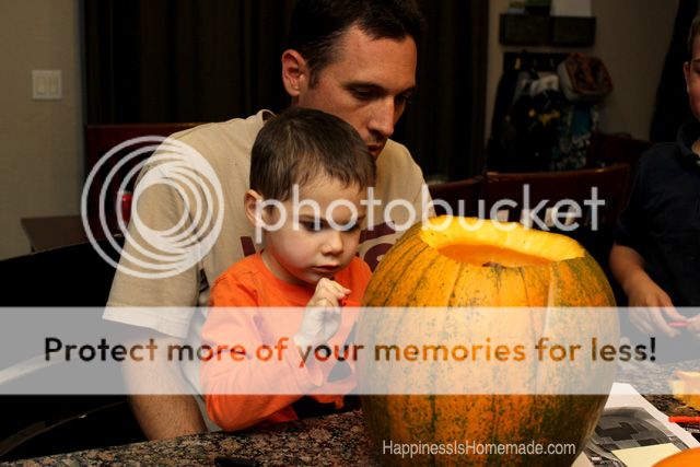 father and son on lap carving a pumpkin together