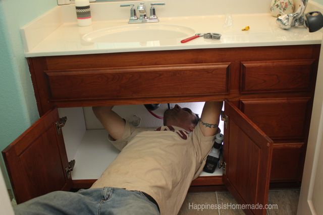 man working hard hooking up new sink faucet 